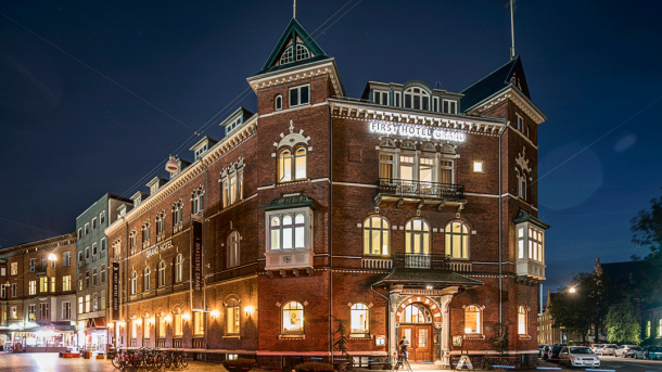 En gammel murstensbygning oplyst af aftenbelysning 