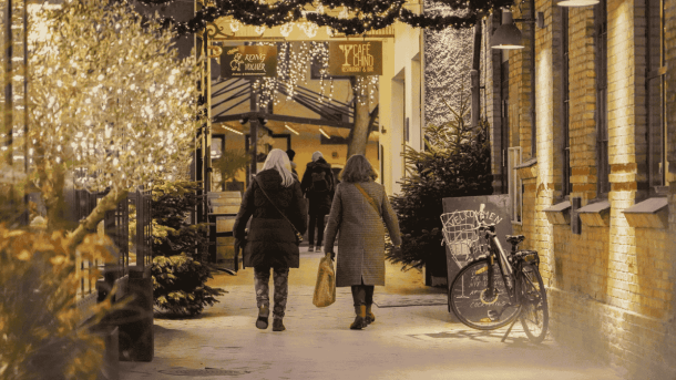 En gade med stemningsfyldt julebelysning og to handlende 