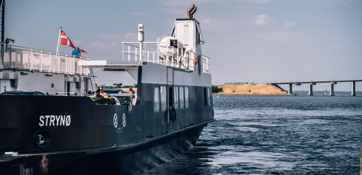  The Strynø ferry on the water with people on board, with a bridge visible ahead.