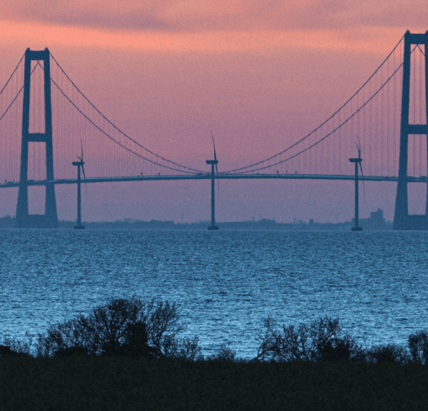Storebæltsbroen i solnedgang, der forbinder Fyn og Sjælland over et stille vand.