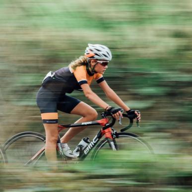 To kvindelige cykelryttere i fuld fart gennem grønt landskab.