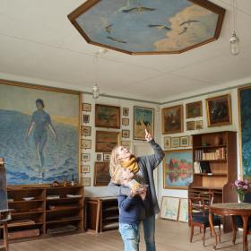 Mor og søn kigger på loftmaleri på Johannes Larsen Museet. De er omgivet af malerier lavet af Johannes Larsen