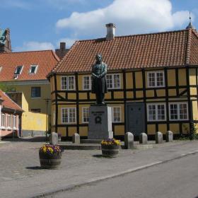 Farverige bygninger i Rudkøbing centrum, hvor en statue af H.C. Ørsted står midt på torvet. 