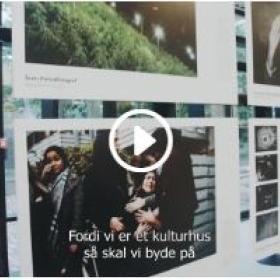 En masse billeder hænger på et glasparti. Der er et videoikon i midten af billedet. 