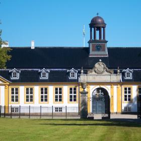 Prangende gul og hvid bygning med klokketårn på det sorte tegltag.