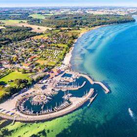 Dronebillede af Lundeborg havn, som er en marina med runde former og med en lille landsby tæt ved