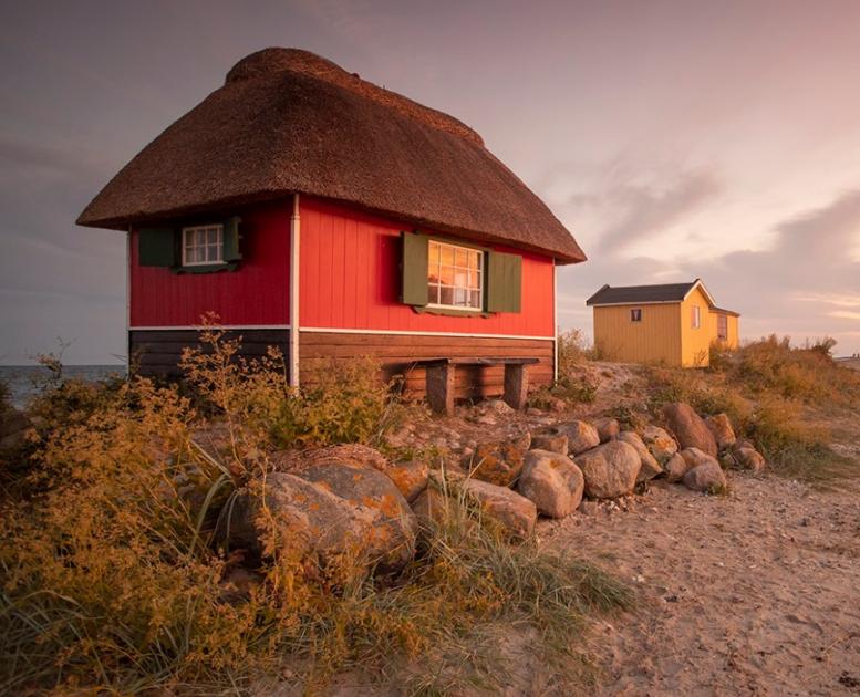 Et rødt og et gult badehus i pink solnedgang ved Eriks Hale ved Marstal, Ærø.