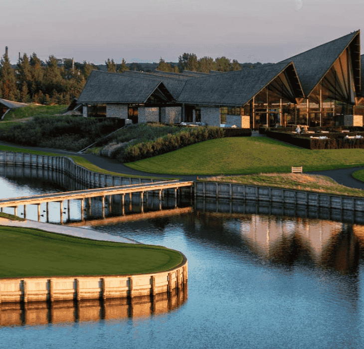 En golfbane med sø og stor ny-nordisk bygningskompleks